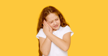 Gyermek fájdalmas arccal fogja a fülét középfülgyulladás miatt